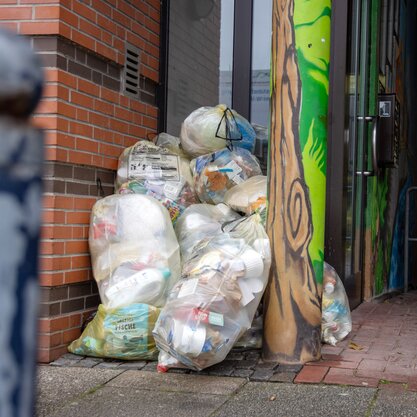 Mehrere gelbe Säcke, in denen Verkaufsverpackungen enthalten sind. Die Säcke sind gestapelt vor einem Hauseingang. | © Die Bremer Stadtreinigung