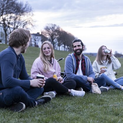 Zwei Frauen und zwei Männer sitzen mit Getränken am Bremer Osterdeich. | © Die Bremer Stadtreinigung